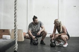Couple with kettlebells in cross training gym